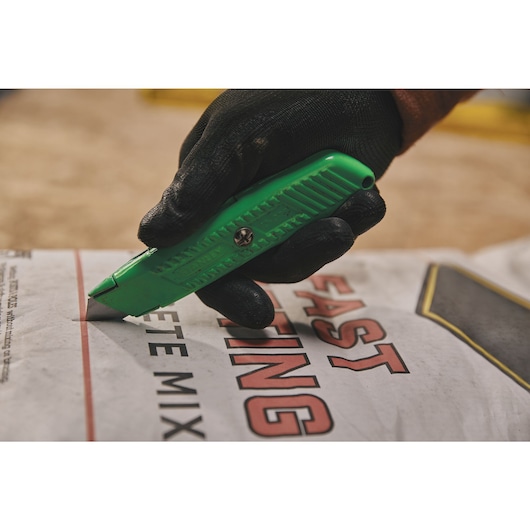 Overhead view of 5 and 7 eighths inch High visibility retractable utility knife opening concrete packet.