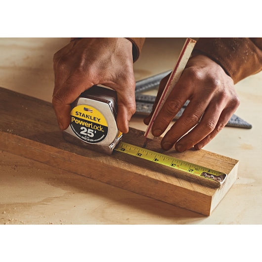 25 foot powerlock tape measure being used by a person to measure wood length.