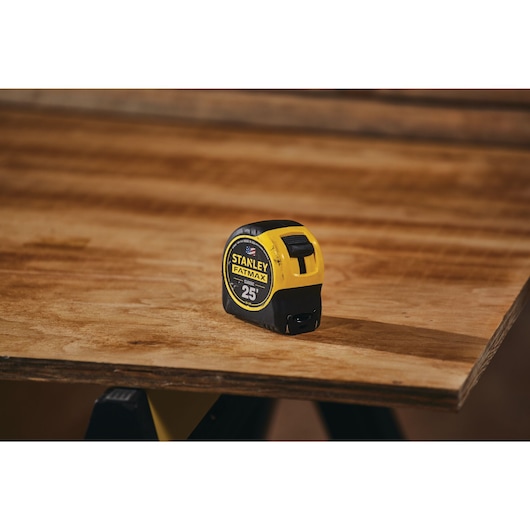 25 foot FATMAX classic tape measure placed on a wooden table in a construction place.
