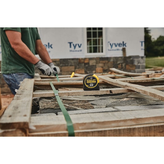 25 foot FATMAX classic tape measure placed on a wood plank at a construction site.