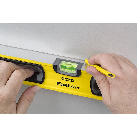 24 inch non magnetic level being used to mark wall.