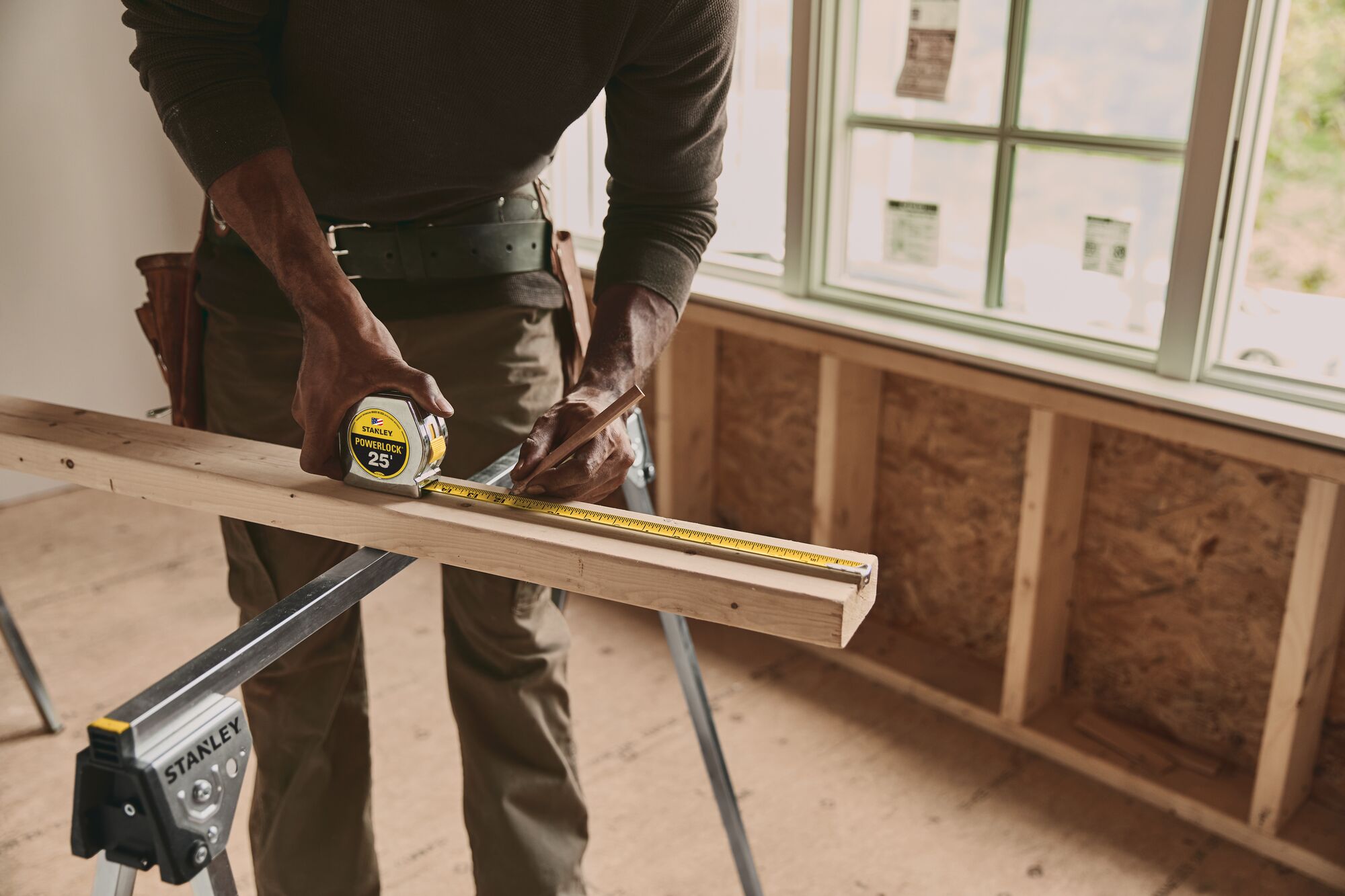 25 foot powerlock tape measure being used by a person to measure wood plank length.