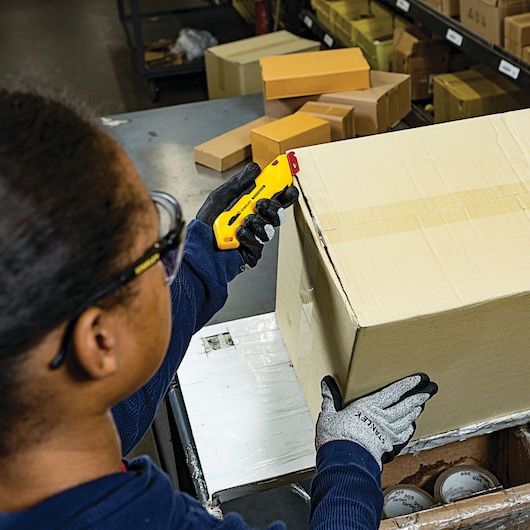 Fatmax left handed box top safety knife being used by a person to cut a box.
