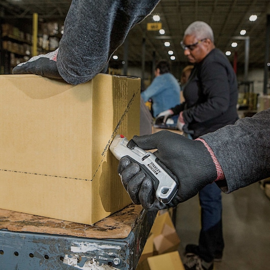 Fatmax premium auto retract tri slide safety knife being used to cut a box.