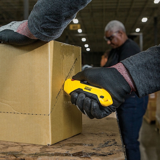 Fatmax auto retract squeeze safety knife being used to cut a box.