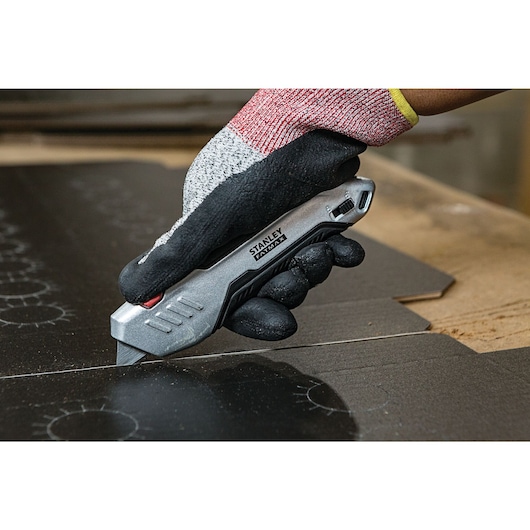 Fatmax premium auto retract squeeze safety knife being used to cut a sheet.