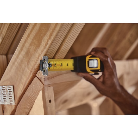 25 feet fatmax auto lock tape being used to measure a wooden beam.