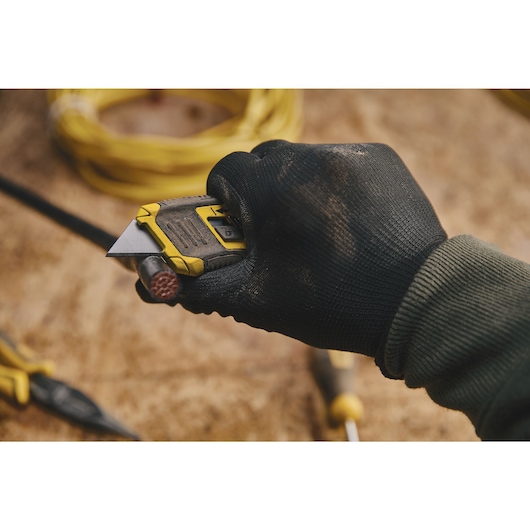 CONTROL GRIP RETRACTABLE UTILITY KNIFE being used for cutting wire.